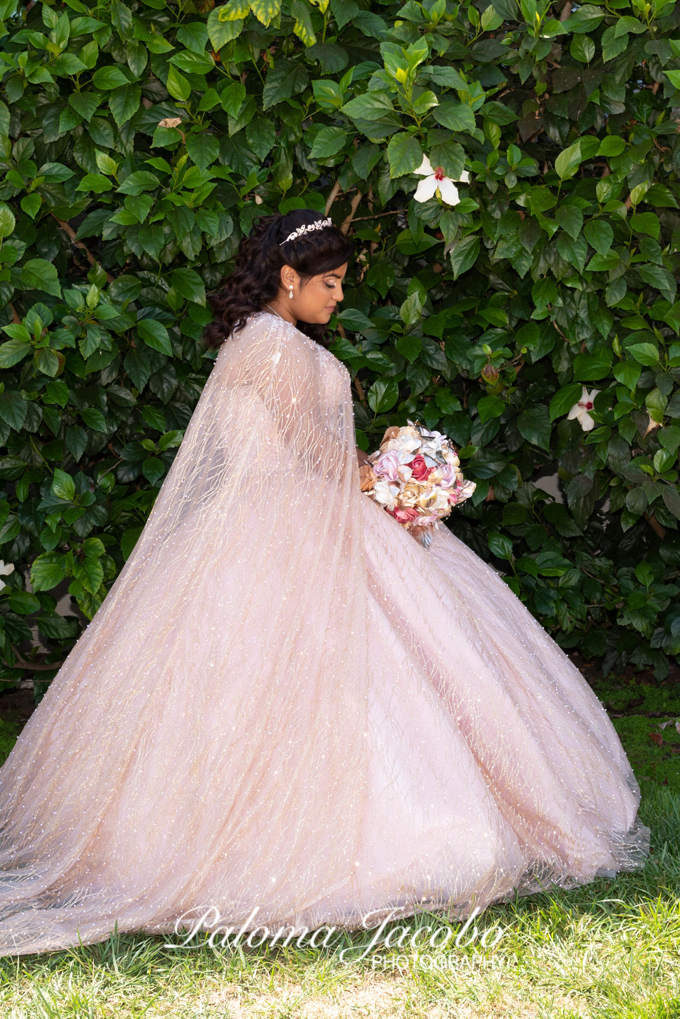 Quinceanera with a green wall background wearing a blush pink dress by Paloma Jacobo Photography