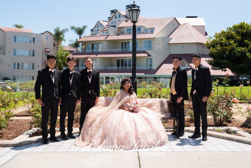 quinceañera sentada acompañada de sus chambelanes