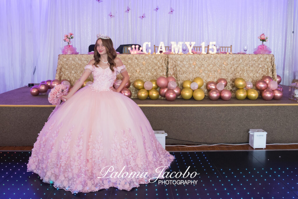 quinceañera posando junto a su mesa de honor en fiesta de quince