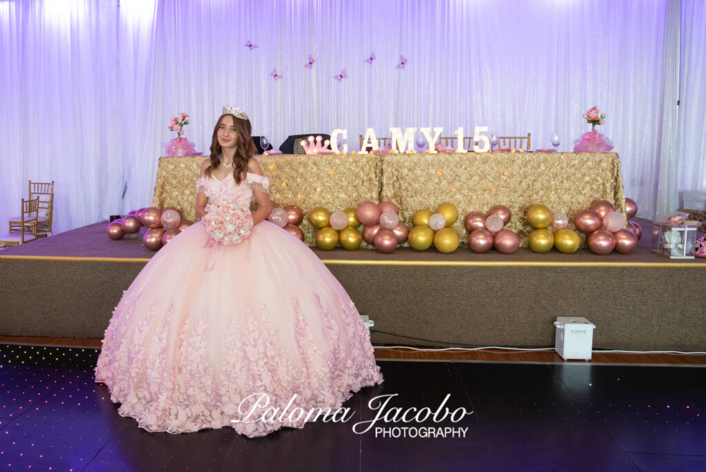 Quinceanera posando frente a la mesa de honor