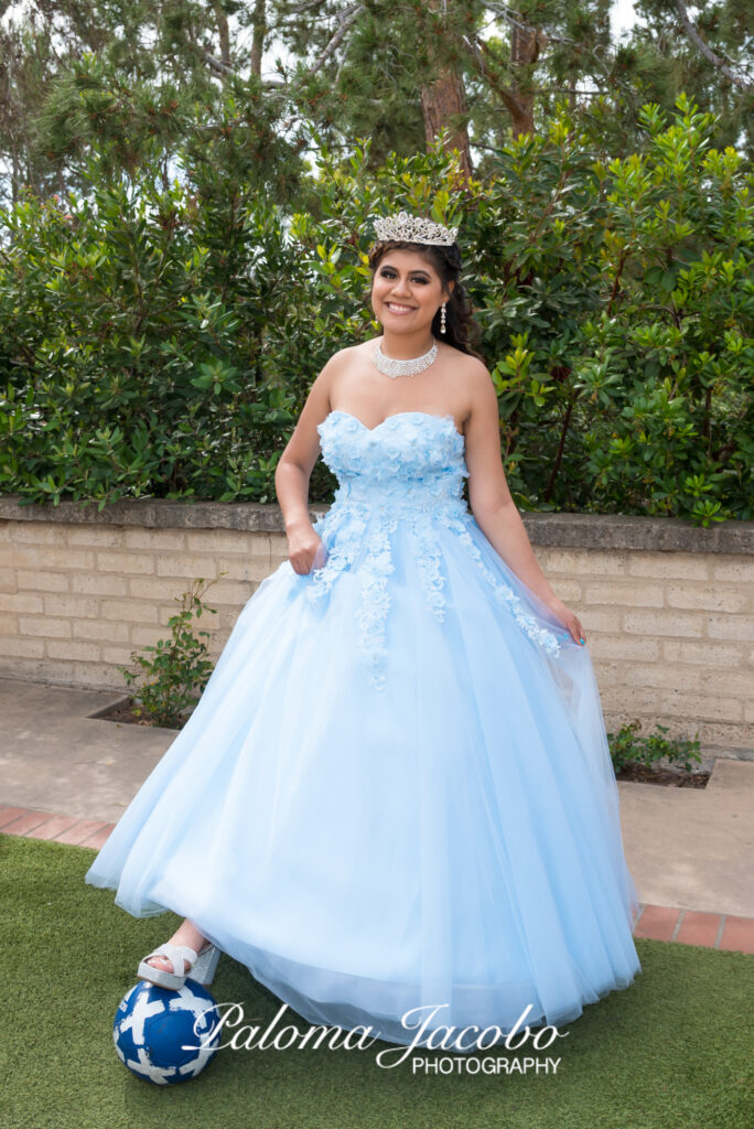 Quinceanera posing with a soccer ball at Balboa Park