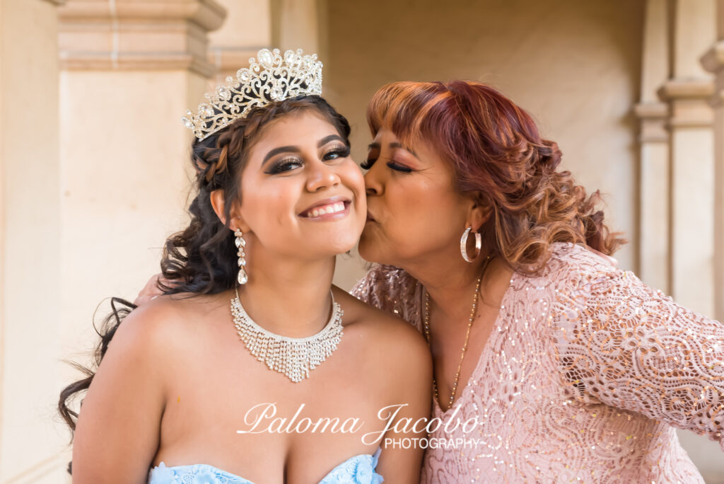Quinceanera receiving a kiss on the cheek from her mom