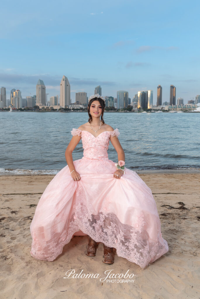 Quinceanera showing off her boots under the pink quince dress at the beach