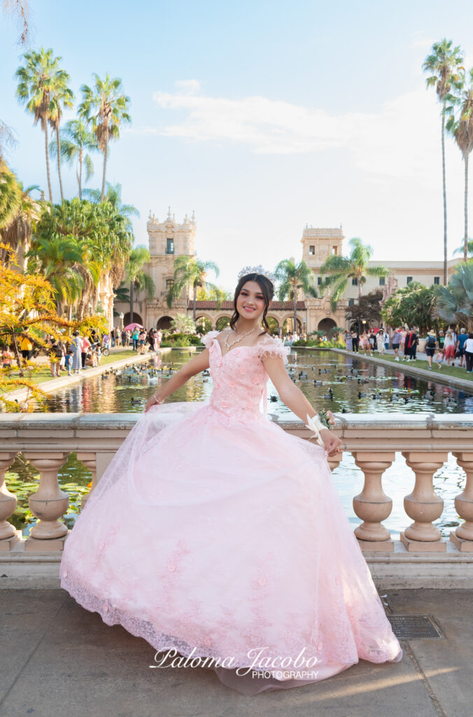 Picture of a Quinceanera wearing an pink dress with the lily pond on the background