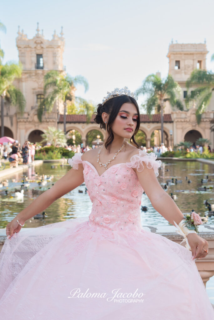 Portrait of a Quinceanera wearing an pink dress with the lily pond on the background
