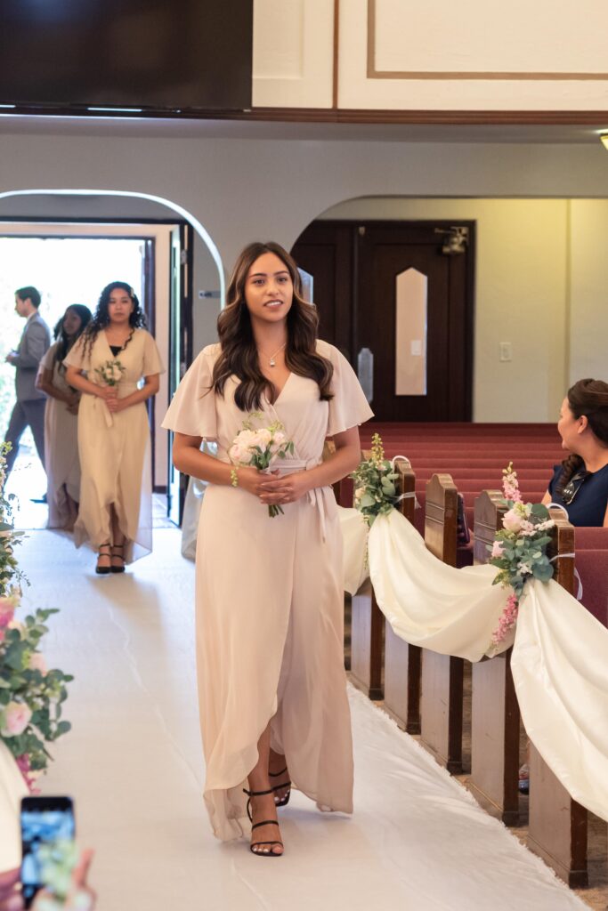 Dama de honor de 15 años entrando a la ceremonia sosteniendo un ramo de flores naturales