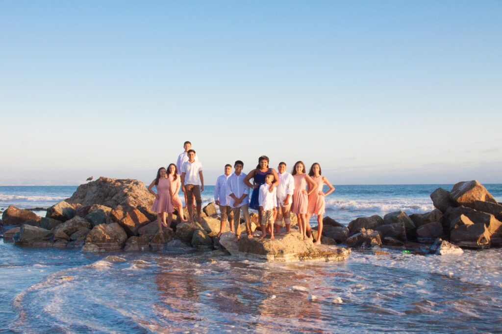 Quinceanera con Damas y Chambelanes arriba de una roca en el mar rodeados de agua en San Diego